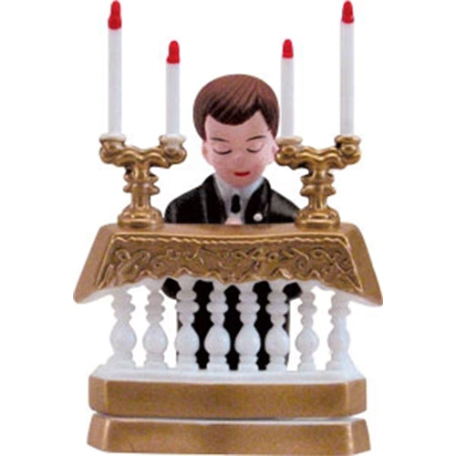 First Communion cake topper with a boy figure standing behind a decorative gold and white altar with red-tipped candles.