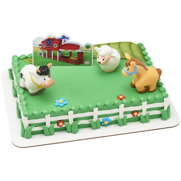 A farm-themed rectangular cake decorated with green frosting, a white fence, flowers, and the animal toppers.