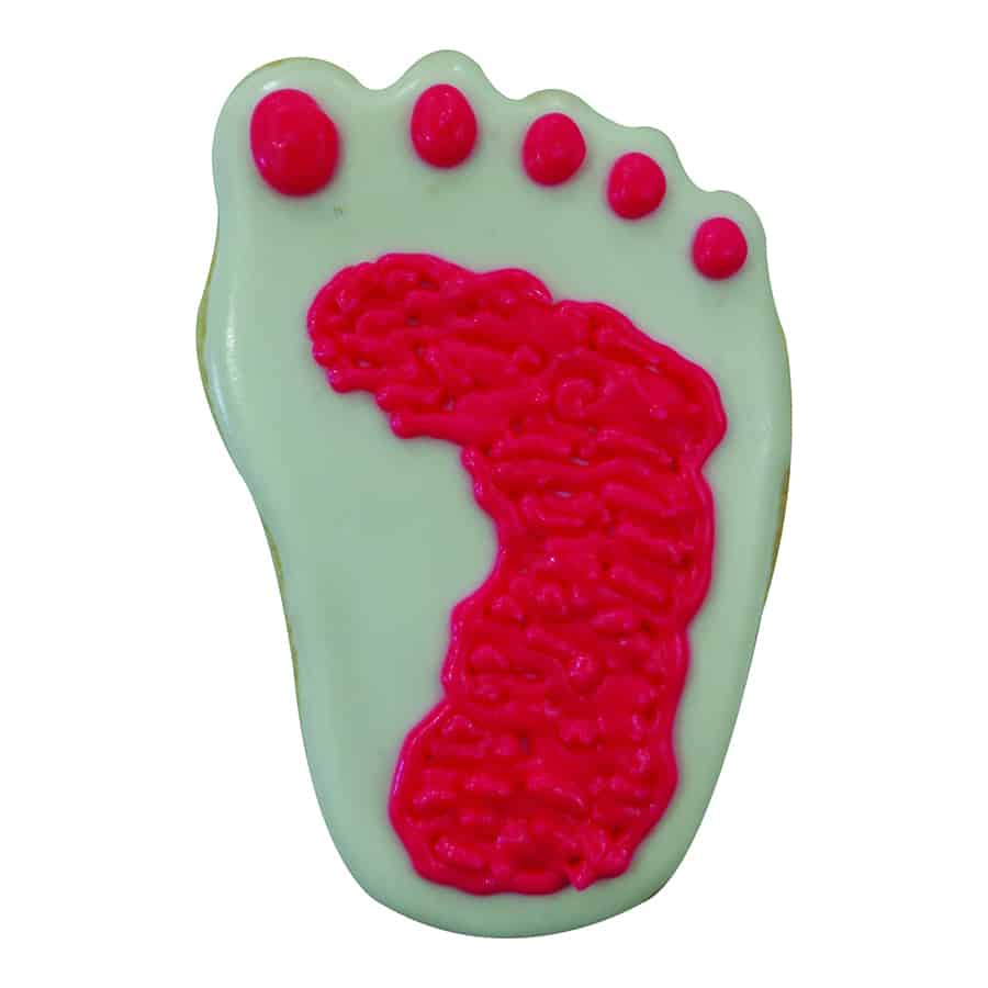 Footprint sugar cookie with light green icing and textured pink detail, resembling a newborn’s footprint.