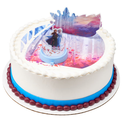 Round cake featuring the Frozen cake topper set, white icing, blue trim, and a snowy-themed edible print design.