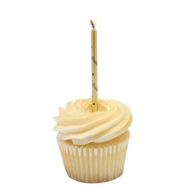 Vanilla cupcake with a tall white buttercream swirl and soft shimmer, topped with a lit gold candle featuring black “Happy Birthday” print.