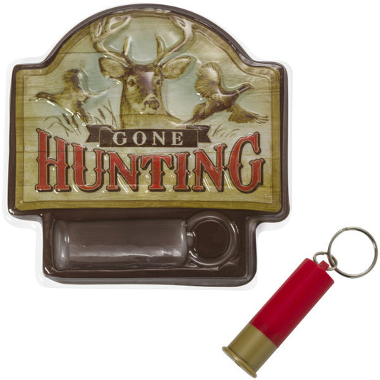 Close-up of the Gone Hunting cake topper plaque with rustic woodland artwork, deer and bird imagery, and a red plastic cartridge shell keychain.