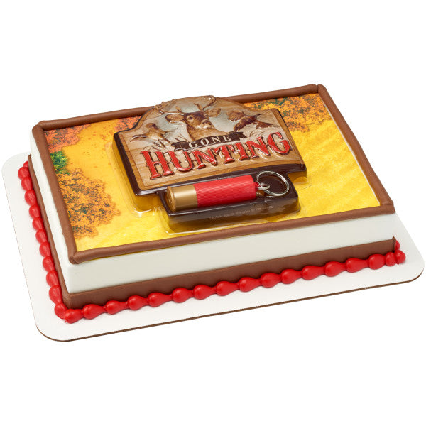 Rectangular cake with fall-toned printed icing, brown border piping, and a centered Gone Hunting cake topper plaque and red cartridge shell keychain.