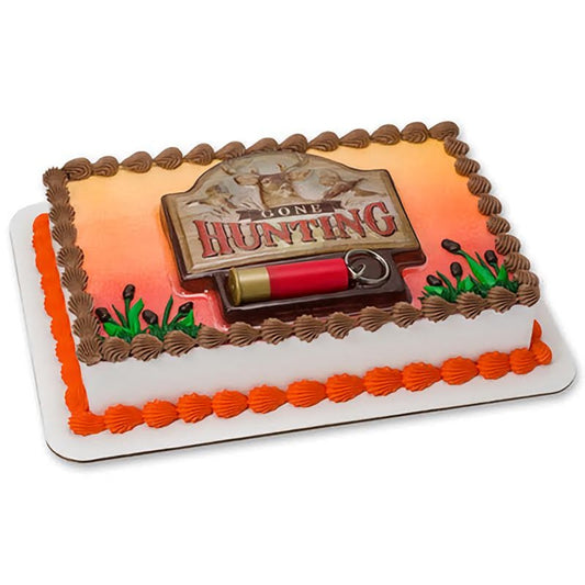 A rectangular cake decorated with a 'Gone Hunting' theme, including a detailed shotgun shell, a hunting dog figurine, and a sign, finished with orange and brown frosting details, perfect for hunting enthusiasts and outdoor-themed events.