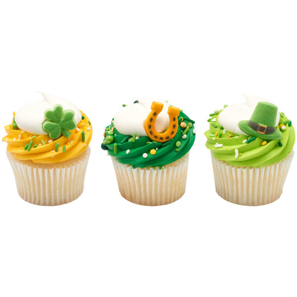 St. Patrick’s Day sugar decorations featuring a green leprechaun hat, golden horseshoe, and shamrock, resting on cupcakes.