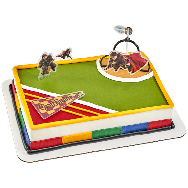 A rectangular Quidditch-themed cake decorated with a green field design, Gryffindor pennant, and the Harry Potter™ Quidditch DecoSet.