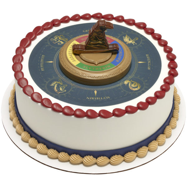 A round cake decorated with the Hogwarts House crest and the Sorting Hat topper in the center.