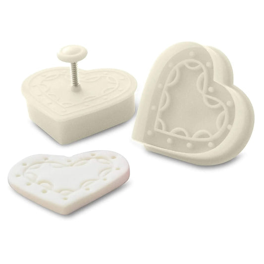 White 2-inch heart plunger stamp cookie cutter shown in three views, including the plunger top with a small button, the heart-shaped cutting edge, and an embossed heart-shaped stamp impression.