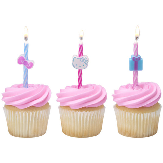 Three vanilla cupcakes topped with pink frosting and Hello Kitty birthday candles featuring bow, face, and gift toppers.