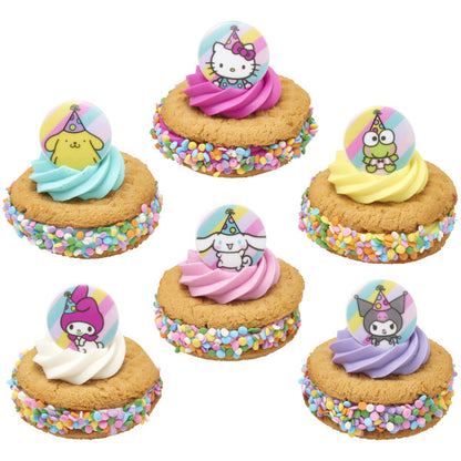 Decorated cookie sandwiches rolled in rainbow sprinkles, each topped with a colorful frosting swirl and a Hello Kitty and Friends cupcake ring topper on a pastel striped circle.