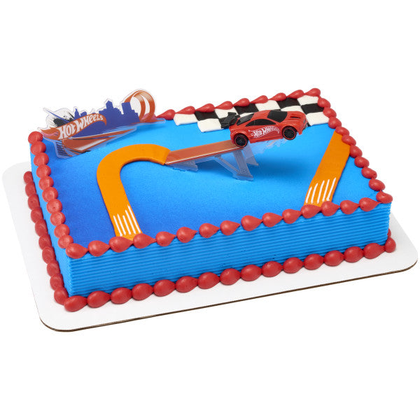 A blue and red racing-themed cake decorated with a Hot Wheels™ stunt ramp and car, set against a checkered flag design.