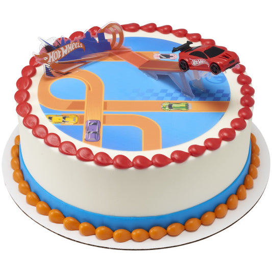 A round cake with a printed racetrack design, featuring a Hot Wheels™ car launching off a stunt ramp.