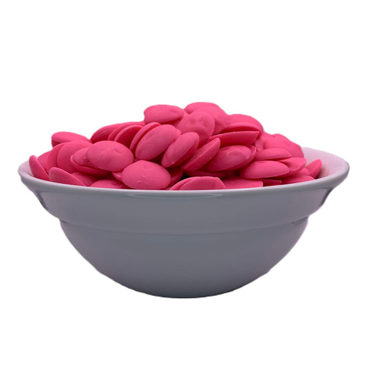 An angled front view of a bowl full of hot pink chocolate melting wafers, showcasing the bright pink wafers that add a vibrant hue to desserts and candies.