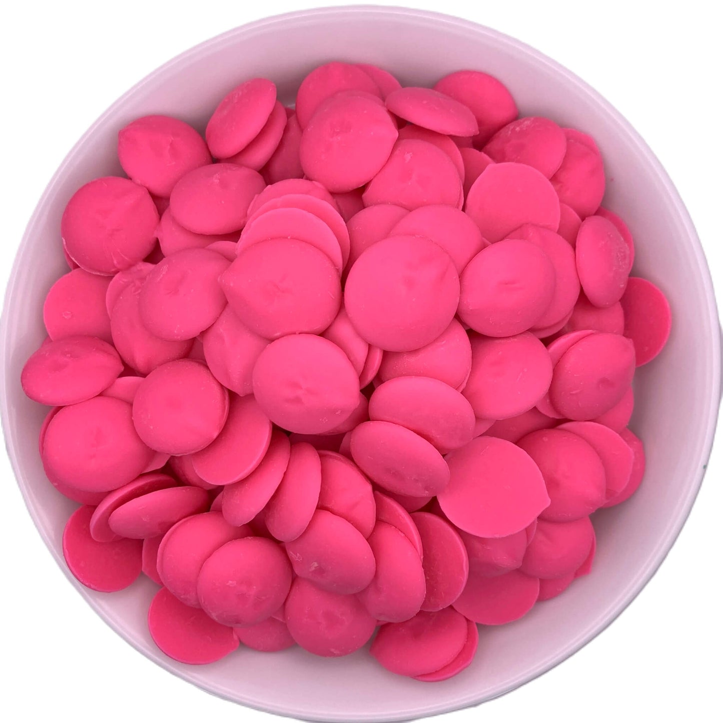 Overhead view of a white bowl filled with hot pink chocolate melting wafers, showing a vibrant and uniform pink color ideal for themed party treats or special occasion confections.