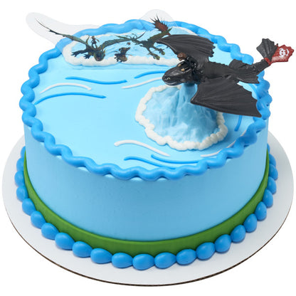 Round blue cake decorated with Toothless dragon topper and flying dragon pick for a How to Train Your Dragon birthday.