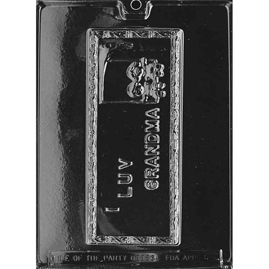 Clear plastic chocolate mold with one long rectangular cavity that says “I Luv Grandma” and includes a small flower pot design.