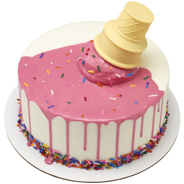 Round white cake with pink drip icing and rainbow sprinkles, topped with an upside-down yellow ice cream cone layon surrounded by pink frosting.