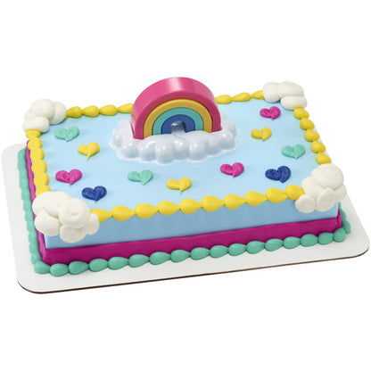 Rectangular sheet cake with light blue icing, yellow piped border, pastel heart decorations, and a rainbow topper on a white cloud tray centered on top.