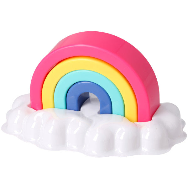 Stackable rainbow cake topper with pink, yellow, teal, and blue arch pieces sitting in a glossy white cloud-shaped tray on a white background.