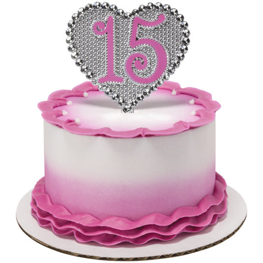 Pink ombre cake with ruffle fondant detailing topped with silver heart-shaped "15" Quinceañera cake topper.