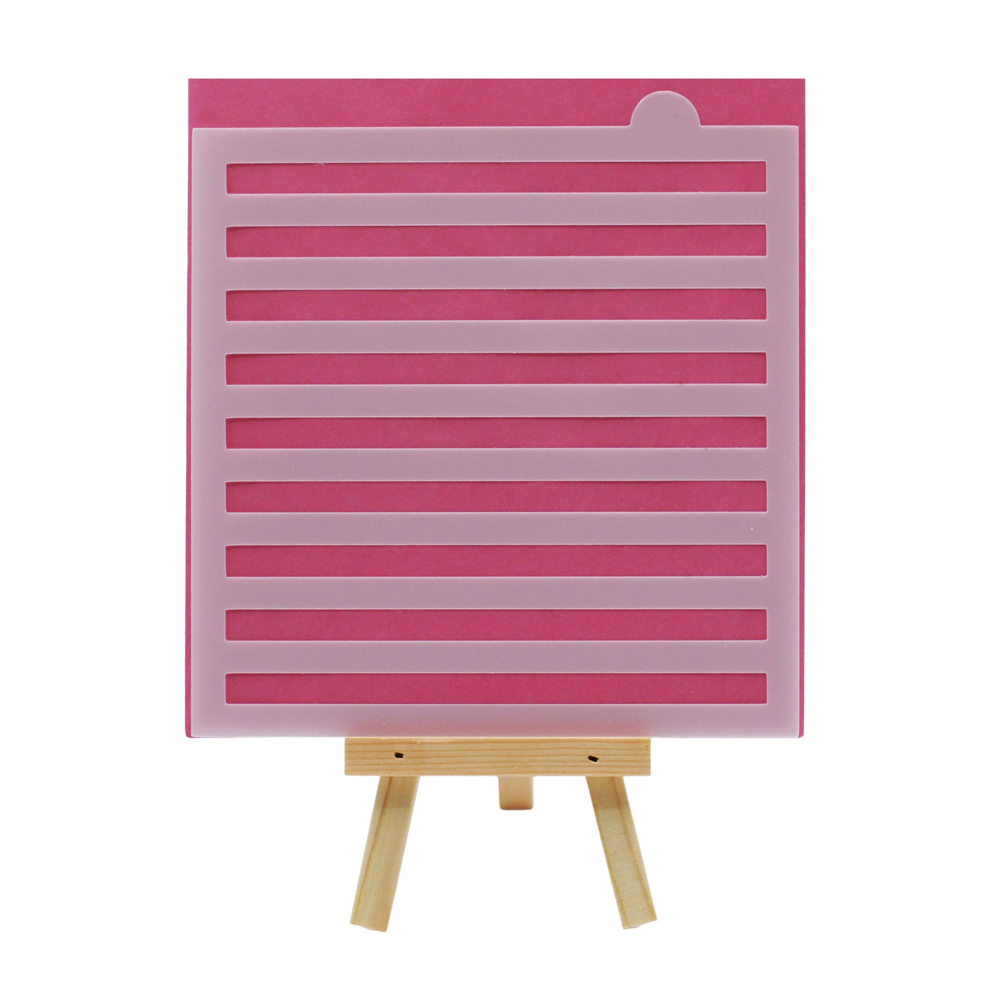 Large stripe cake and cookie stencil with evenly spaced horizontal cutout lines, shown in translucent plastic against a pink background on a small wooden easel.