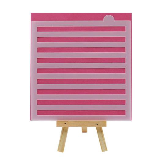 Large stripe cake and cookie stencil with evenly spaced horizontal cutout lines, shown in translucent plastic against a pink background on a small wooden easel.