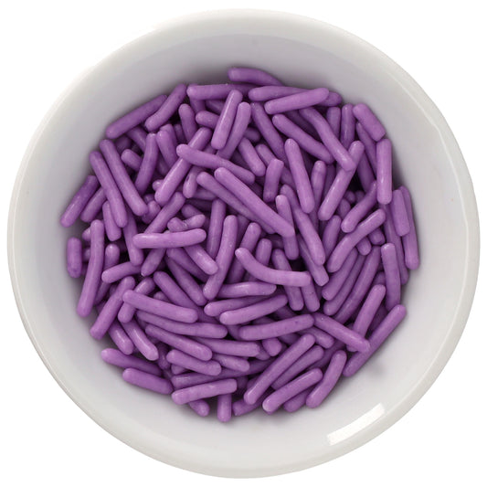 White bowl filled with soft lavender purple Natural Dyed Made Simply™ rod-shaped sprinkles, shown in a close-up overhead view on a white background.