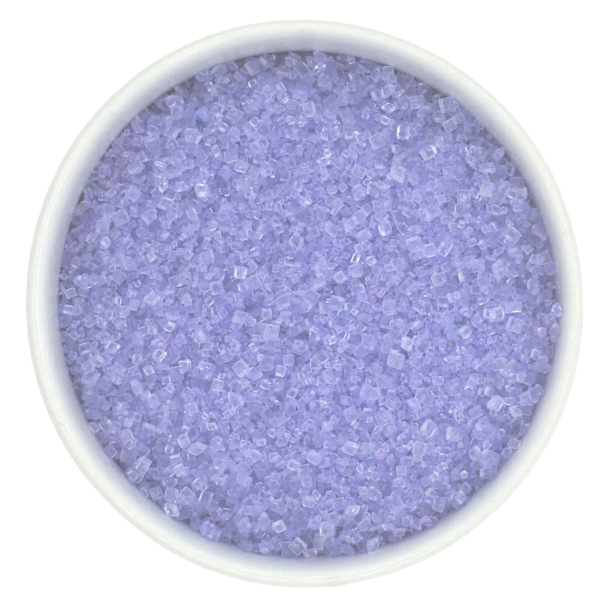 Top-down view of a white bowl filled with lavender coarse sanding sugar crystals, showing pale purple, chunky granules with a clear sparkling shine.