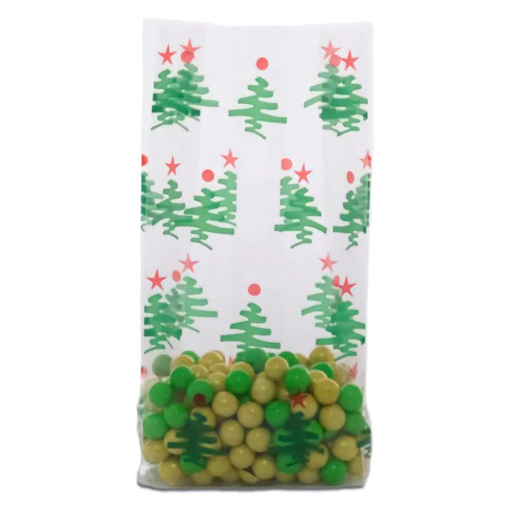 A medium-sized cellophane treat bag filled with green and yellow candies, visible through the transparent lower half. The upper half of the bag has a festive design featuring green Christmas trees and red stars on a white background. The trees are stylized and spaced apart, creating a pattern that evokes a cheerful holiday theme.