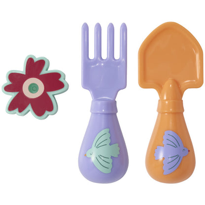 A pastel-colored toy fork and shovel with bird designs and a red flower candle holder, designed as a cake decoration.