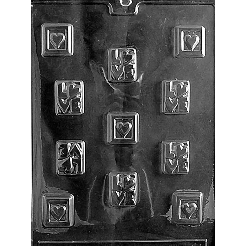 Clear plastic chocolate mold with multiple small square cavities, including raised “LOVE” squares and framed heart squares arranged in rows.