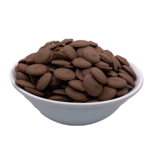 A white bowl filled to the brim with Merckens Coco Lite milk chocolate melting wafers, showcased from a front angle, highlighting the smooth, creamy discs ideal for creating decadent chocolate treats.