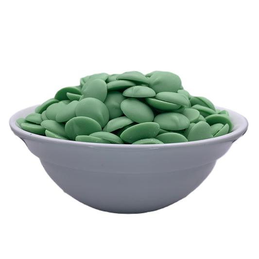 Front view of a bowl of Merckens green chocolate melting wafers, showing the vibrant green discs ready for creating festive confections or holiday treats.