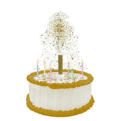 White frosted round cake with gold trim and colorful birthday candles, topped with a gold party popper releasing a shower of metallic edible confetti.
