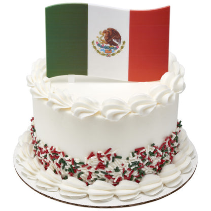 White frosted cake decorated with red, white, and green sprinkles, topped with a plastic Mexican flag cake topper.