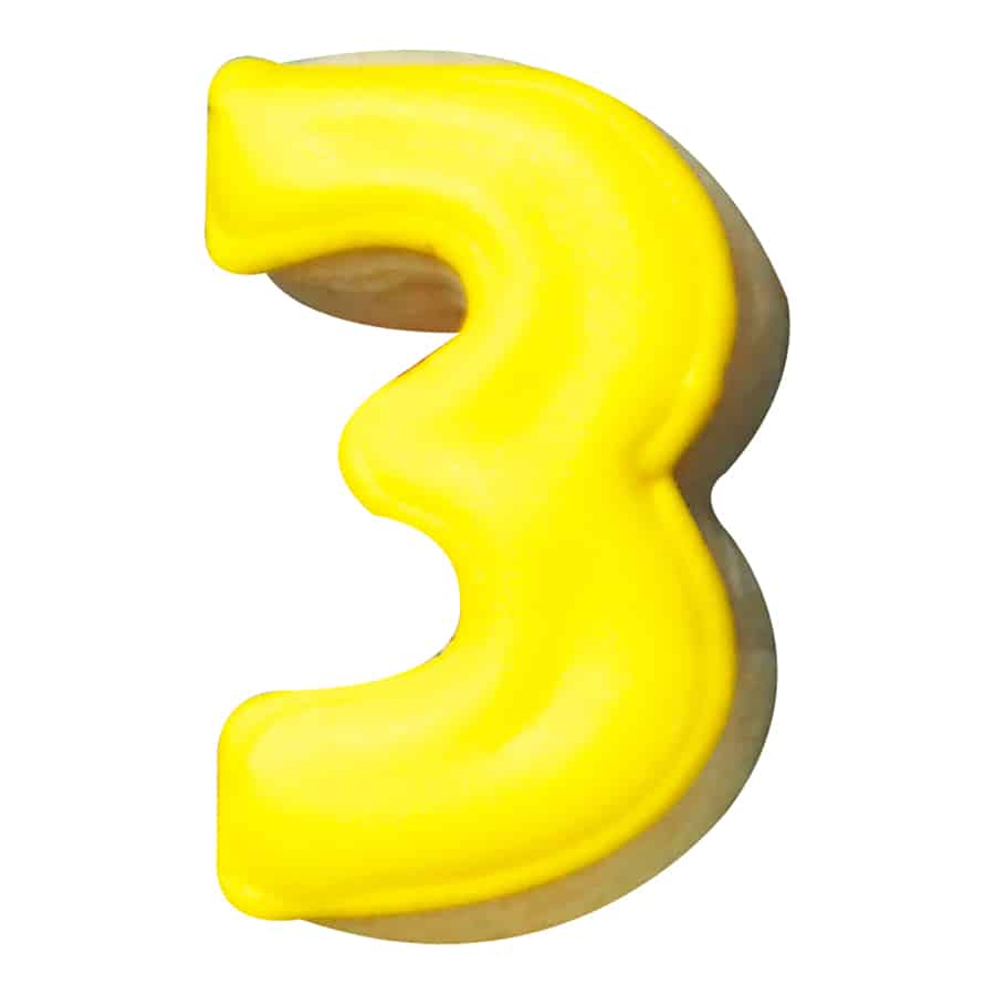 A close-up of a yellow number "3" cookie with glossy icing.