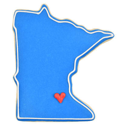 Blue Minnesota state-shaped cookie with a small red heart marking a location, made using the Minnesota state cookie cutter.