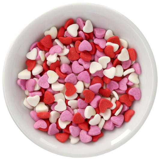 Top-down view of a white bowl filled with red, pink, and white heart-shaped sprinkles on a white background.