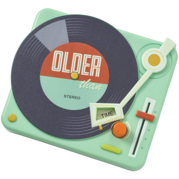 A vintage-inspired record player cake topper in mint green with a vinyl design reading "Older Than Time."