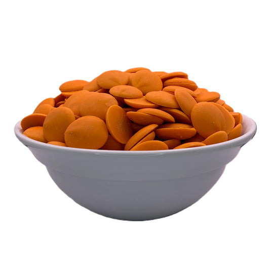 White ceramic bowl filled with smooth, orange candy melts used for baking, molding, and cake decorating, isolated on white background.