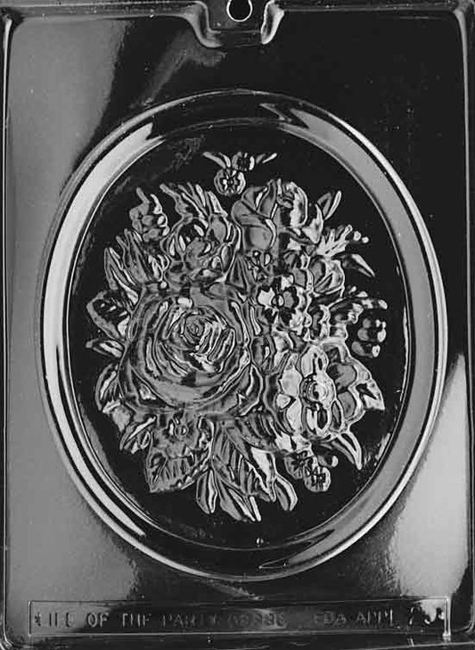 Clear plastic chocolate mold featuring a large oval frame with a raised bouquet of roses and assorted flowers; deep relief for painting and dusting; cavity size about 6 1/8 x 7 3/8 x 1 inches, producing a ~5.8 oz floral plaque.