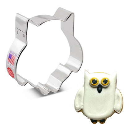 Owl cookie cutter alongside a decorated owl-shaped cookie with white icing, yellow eyes, and black details.