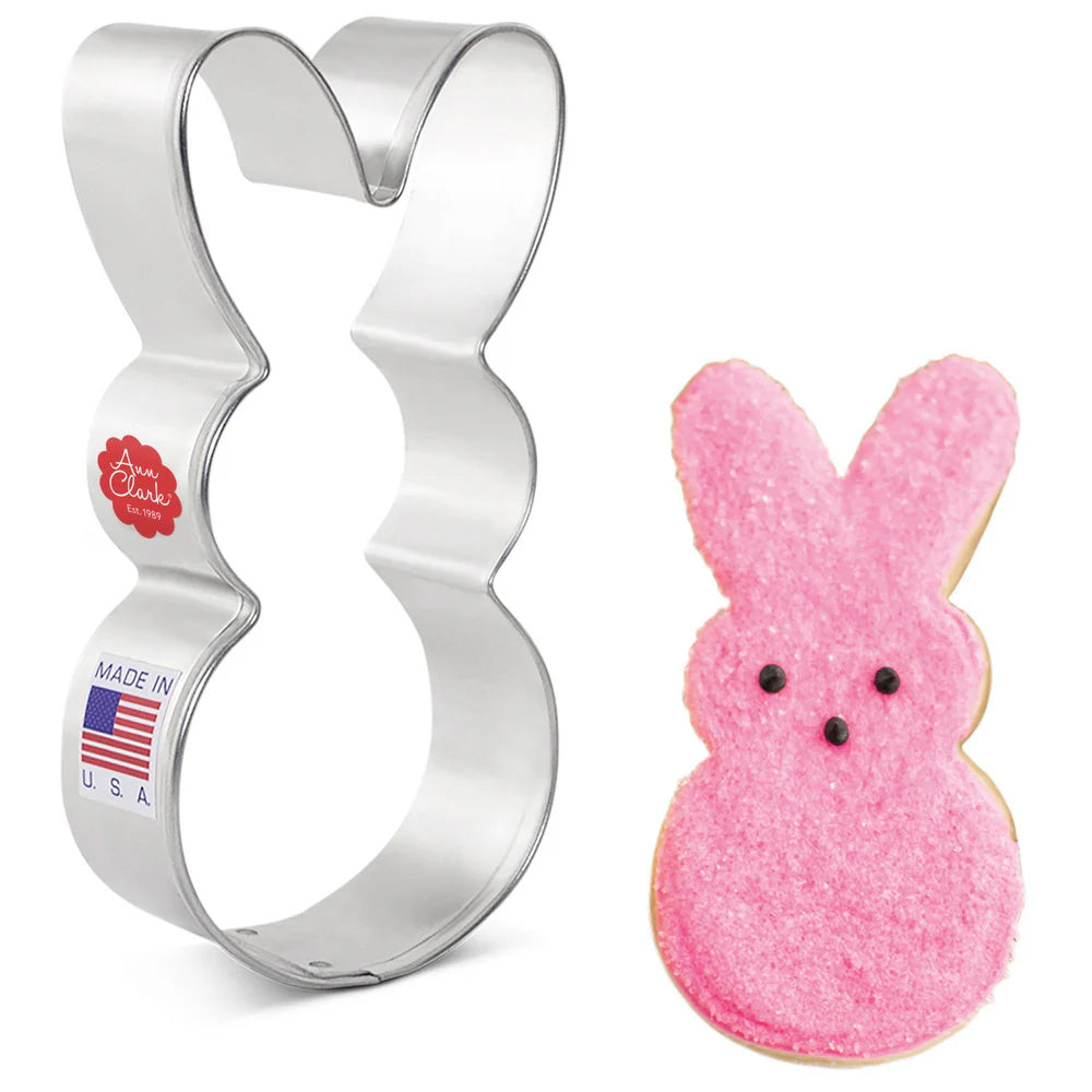 Peep Easter Bunny cookie cutter alongside a pink sugar-coated bunny-shaped cookie with black eyes.