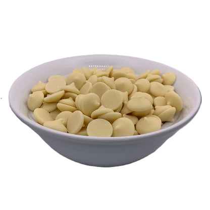 White ceramic bowl filled with smooth, pale yellow white chocolate wafers, each with a rounded top and glossy finish, set against a white background.