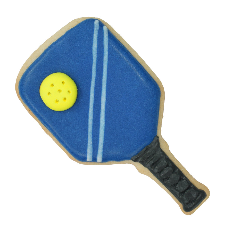 Decorated pickleball paddle cookie with deep blue icing, two light blue stripes, a textured black handle, and a small yellow perforated ball detail on the paddle.