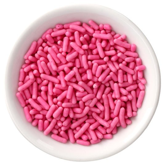 Top-down view of a white bowl filled with bright pink naturally dyed rod-shaped sprinkles on a white background.