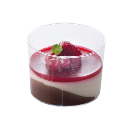 Clear plastic dessert cup filled with layered dessert in chocolate, cream, and berry-red layers, topped with raspberries and a mint leaf.