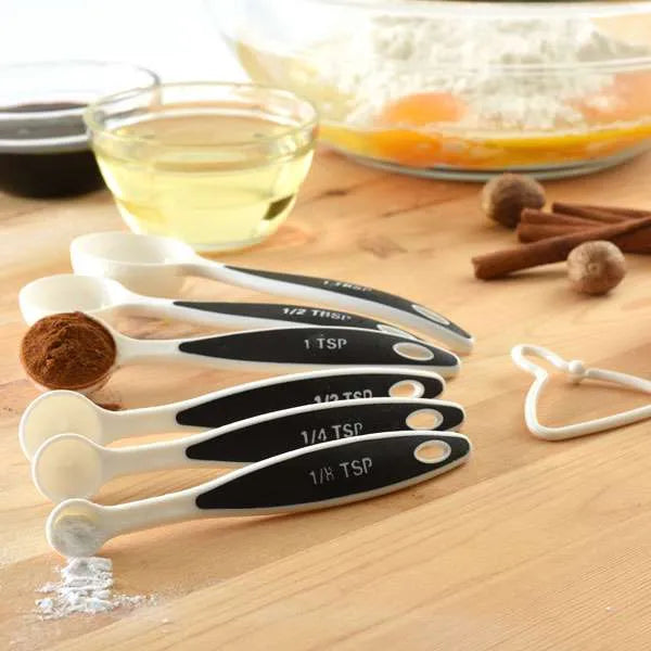 Measuring spoons on a counter with spices and baking ingredients in the background
