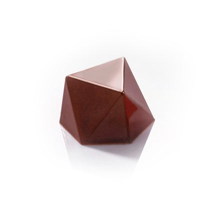 Finished geometric chocolate bonbon with multiple flat facets and a glossy dark chocolate finish, shown on a white reflective surface.