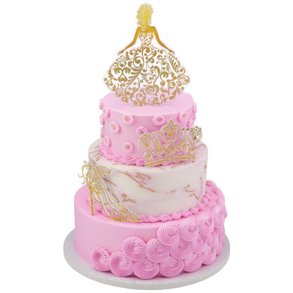 Tiered pink and white cake decorated with gold Quinceañera toppers: girl, crown, and high heel.